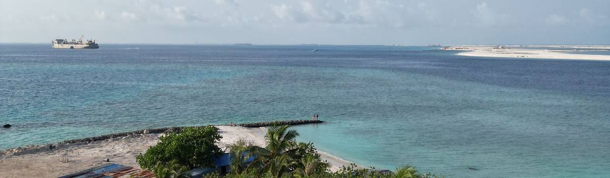 Hopper dredger working on the horizon beyond the reef